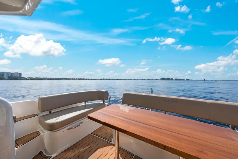 Nauti-lin Yacht Photos Pics 2016 Carver C37 Coupe yacht deck with seating and table, overlooking serene water and blue sky.