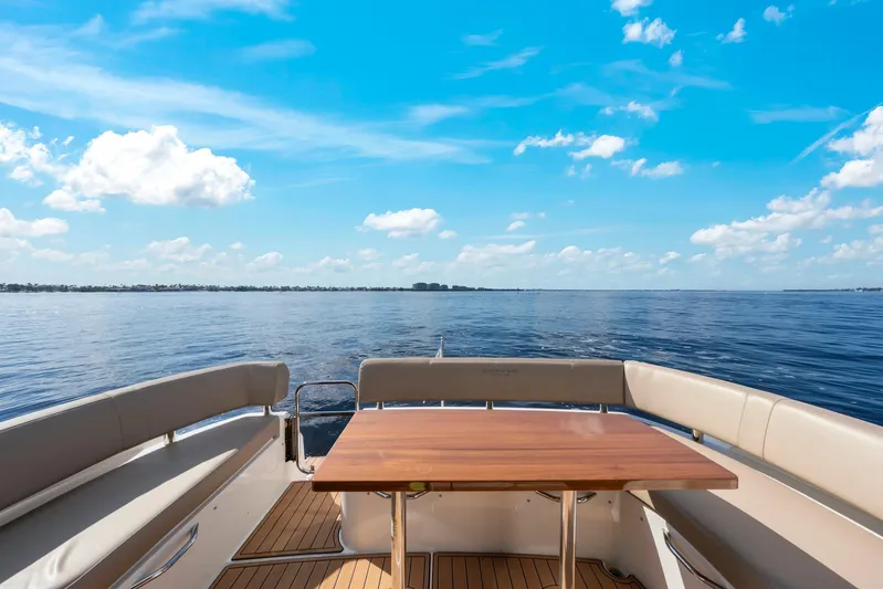 Nauti-lin Yacht Photos Pics 2016 Carver C37 Coupe yacht deck with table, overlooking serene ocean and blue sky.