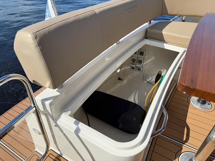 Nauti-lin Yacht Photos Pics 2016 Carver C37 Coupe storage compartment with beige seating and wooden deck.