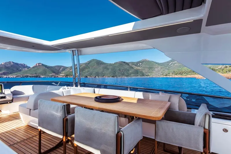  Yacht Photos Pics Luxurious Absolute Navetta 73 yacht deck with dining area, overlooking serene blue waters and green hills.