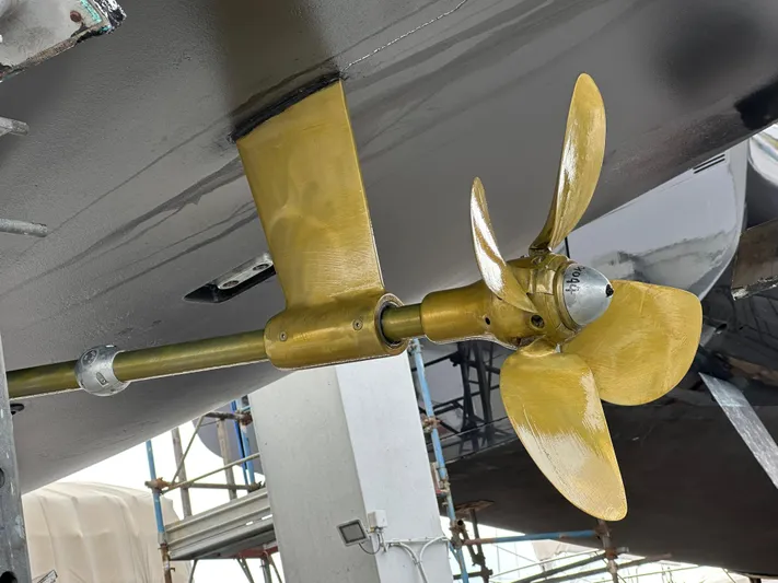 Juul Yacht Photos Pics Gold-colored propeller of a 2019 CNB 66 yacht, displayed in a shipyard setting.