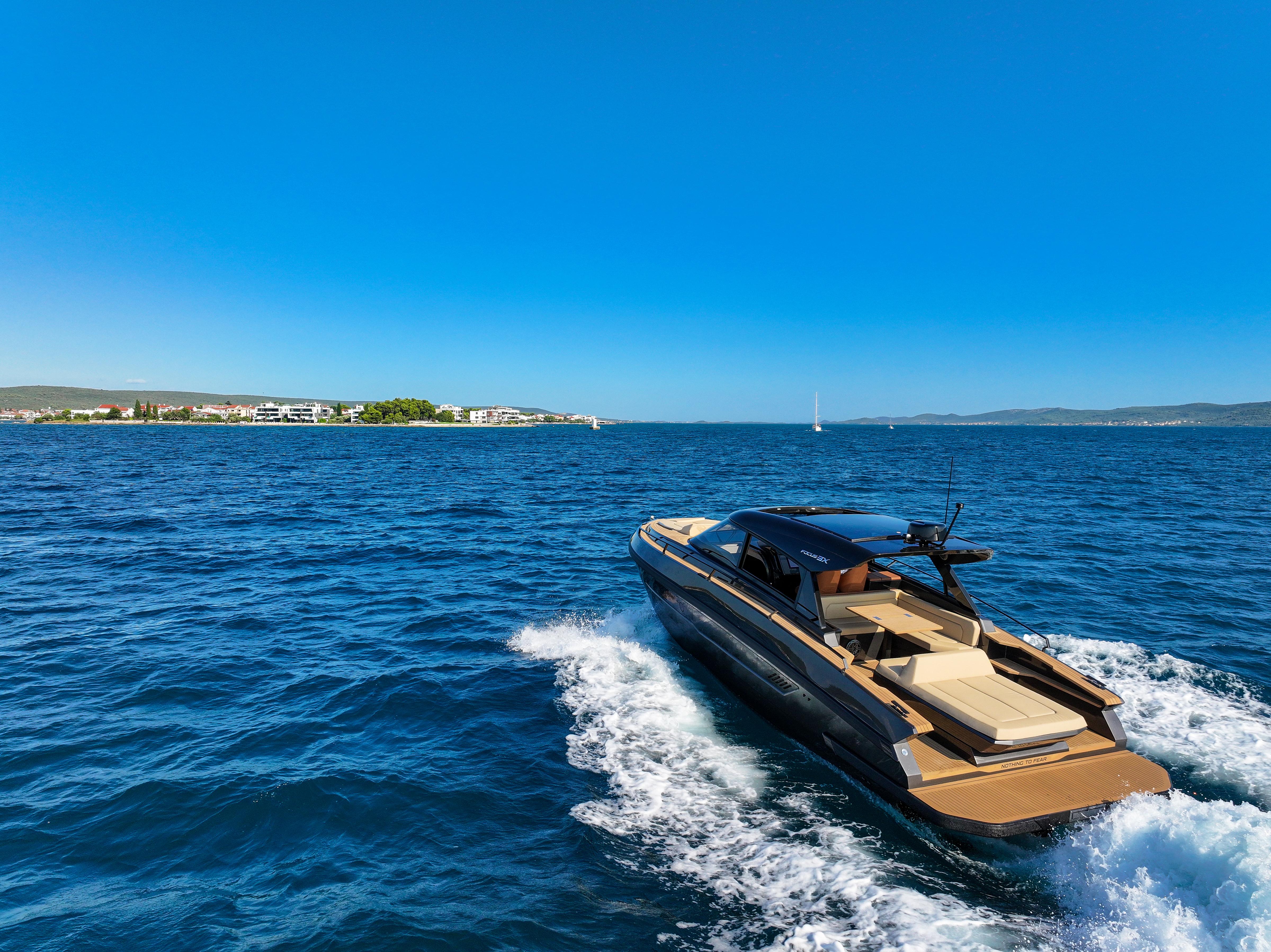 Luxurious Focus 3X yacht cruising on blue ocean near coastal town, 2026 model.