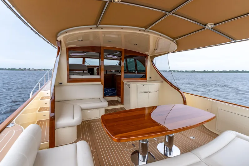 Zephyr Yacht Photos Pics 2018 Palm Beach Motor Yachts PB55 interior with elegant seating and wooden table on open water.