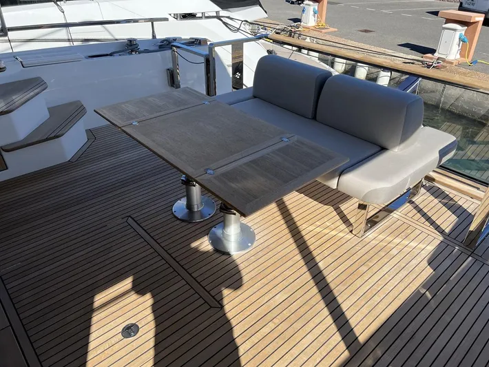  Yacht Photos Pics Prestige X60 2023 yacht deck with wooden flooring, cushioned seating, and a foldable table.