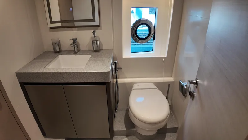  Yacht Photos Pics Luxurious bathroom in 2024 Gulf Craft Nomad 65 yacht with modern fixtures and porthole window.