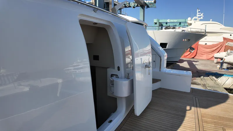  Yacht Photos Pics 2024 Gulf Craft Nomad 65 yacht docked, showcasing sleek white exterior and open cabin door.