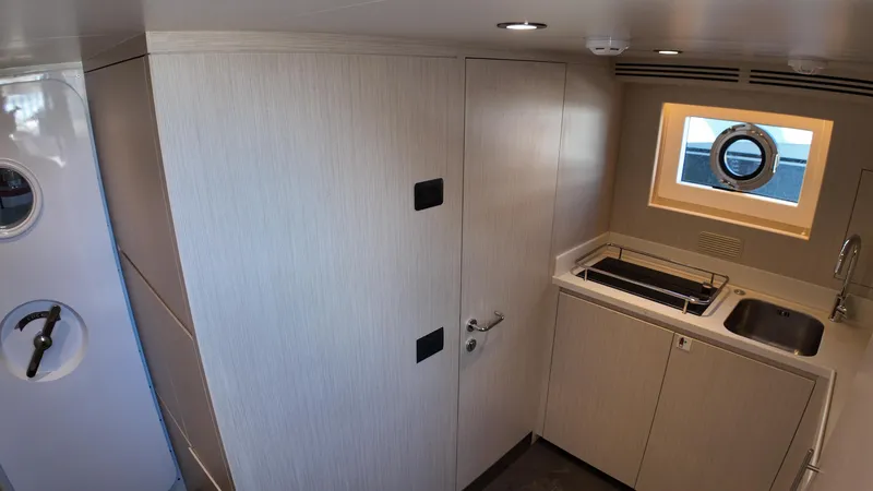  Yacht Photos Pics Interior of 2024 Gulf Craft Nomad 65 yacht, featuring modern kitchenette and porthole window.