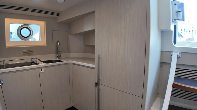 Yacht Photos Pics Modern kitchen interior of 2024 Gulf Craft Nomad 65 yacht, featuring sleek cabinetry and porthole window.