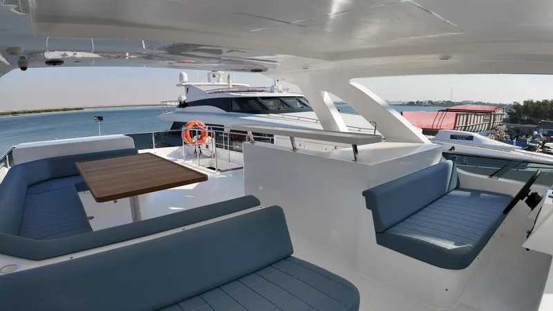  Yacht Photos Pics 2024 Gulf Craft Nomad 65 yacht interior with blue seating and wooden table.