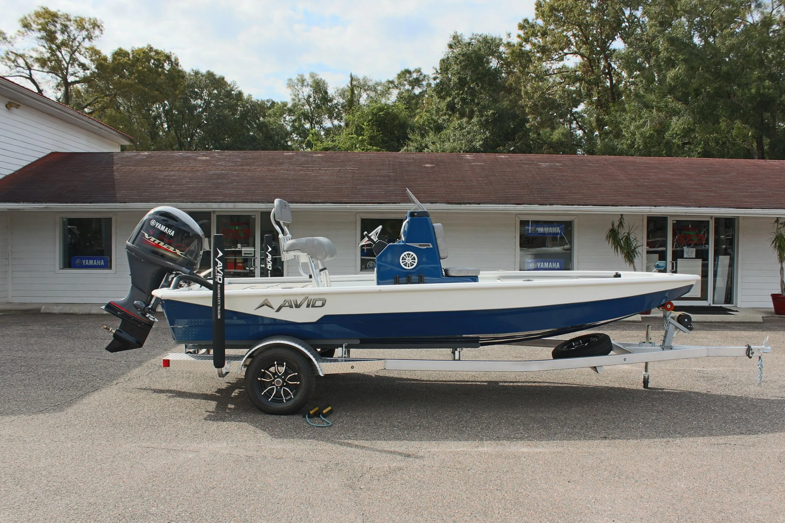 2025 Avid 19 FSX boat on trailer, parked outside a building.
