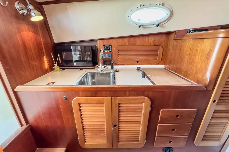 Hobnob Yacht Photos Pics Hinckley Yachts 2001 Picnic Boat Classic 36 interior galley with sink, microwave, and wooden cabinetry.