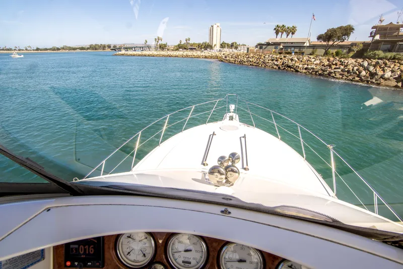 Journeys Edge Yacht Photos Pics 2007 Silverton 36 Convertible yacht navigating clear blue waters near a rocky shoreline.