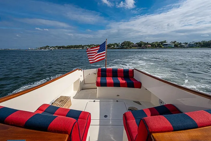Comin' In Hot Yacht Photos Pics Hinckley Talaria 34 boat, 2016 model, with American flag and striped seating on open water.
