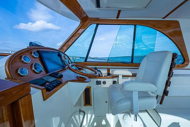 Comin' In Hot Yacht Photos Pics Interior helm of 2016 Hinckley Talaria 34 yacht with wooden dashboard and white captain's chair.