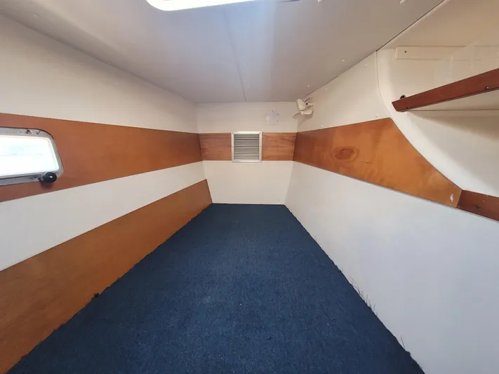 Ki Zen Yacht Photos Pics Interior cabin of 1995 Lagoon TPI 42 yacht with wood paneling and blue carpet.