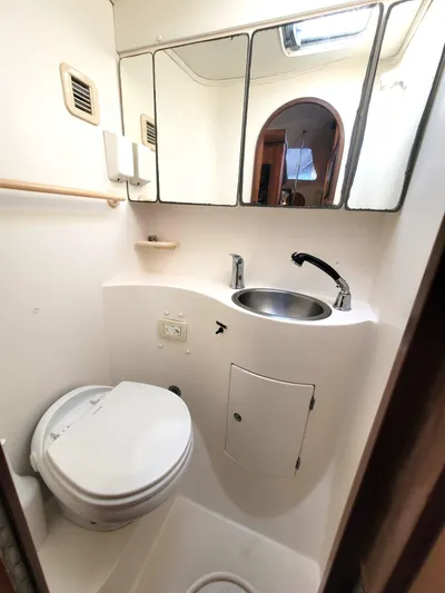 Ki Zen Yacht Photos Pics Compact bathroom in 1995 Lagoon TPI 42 yacht with toilet, sink, and mirror.