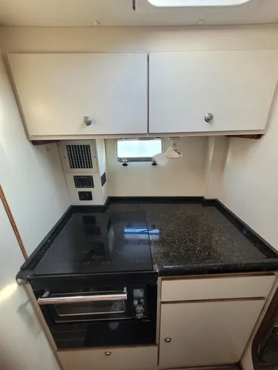 Ki Zen Yacht Photos Pics 1995 Lagoon TPI 42 yacht kitchen with black countertop and white cabinets.