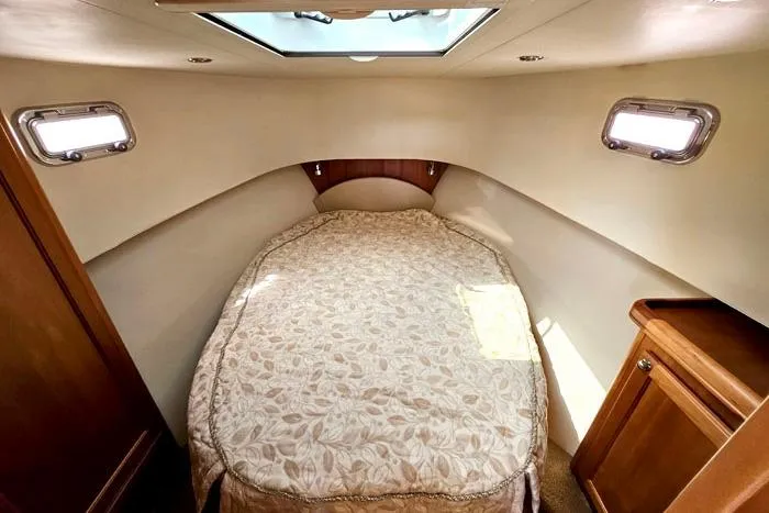  Yacht Photos Pics Cozy cabin interior of 2007 Mainship 34 Trawler with bed and porthole windows.