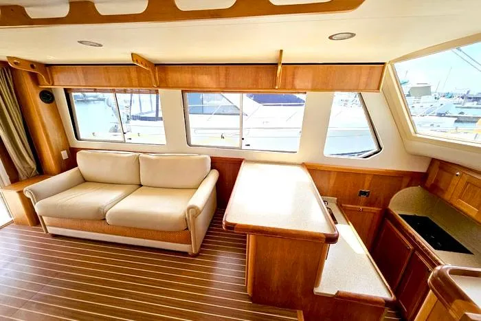  Yacht Photos Pics Interior of 2007 Mainship 34 Trawler with sofa, wooden cabinetry, and large windows.