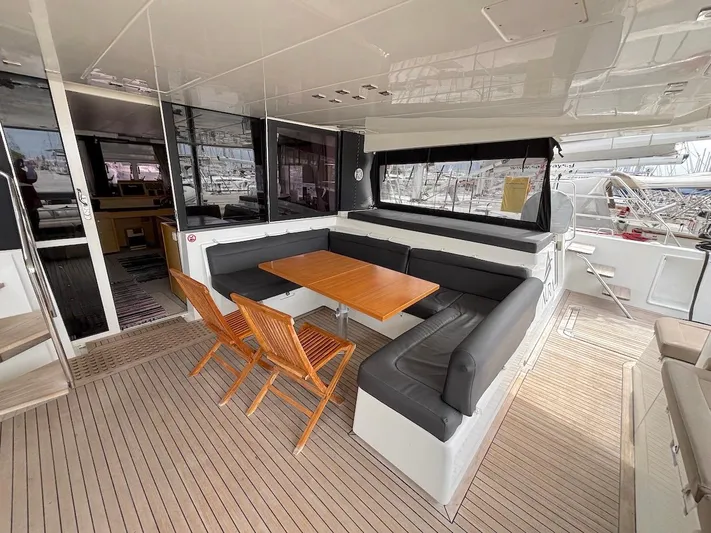 Avra Yacht Photos Pics Spacious deck seating area on 2014 Lagoon 560 S2 catamaran with wooden table and chairs.