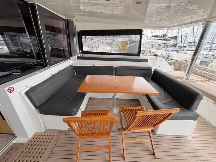 Avra Yacht Photos Pics Outdoor seating area on a 2014 Lagoon 560 S2 yacht with wooden table and chairs.
