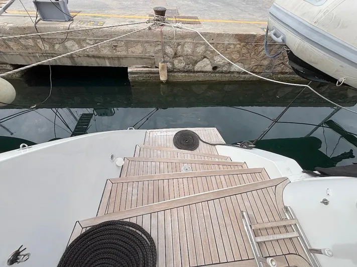 Avra Yacht Photos Pics Lagoon 560 S2 yacht deck with wooden steps and mooring ropes, docked at a marina.