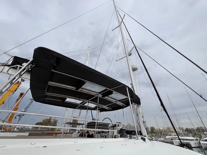 Avra Yacht Photos Pics 2014 Lagoon 560 S2 sailboat with black canopy, docked in marina under cloudy sky.