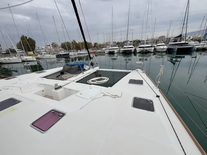 Avra Yacht Photos Pics Lagoon 560 S2 catamaran docked in marina, surrounded by sailboats, overcast sky.