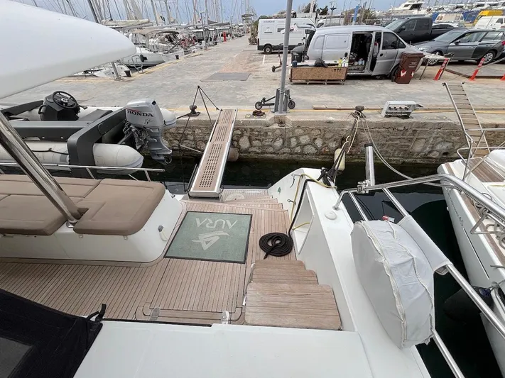 Avra Yacht Photos Pics Lagoon 560 S2 yacht docked at marina, featuring spacious deck and nearby motorboat.