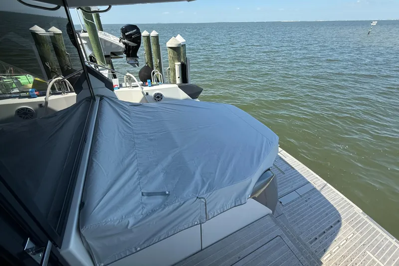  Yacht Photos Pics 2023 Beneteau Gran Turismo 45 yacht docked by the water, covered with a protective tarp.