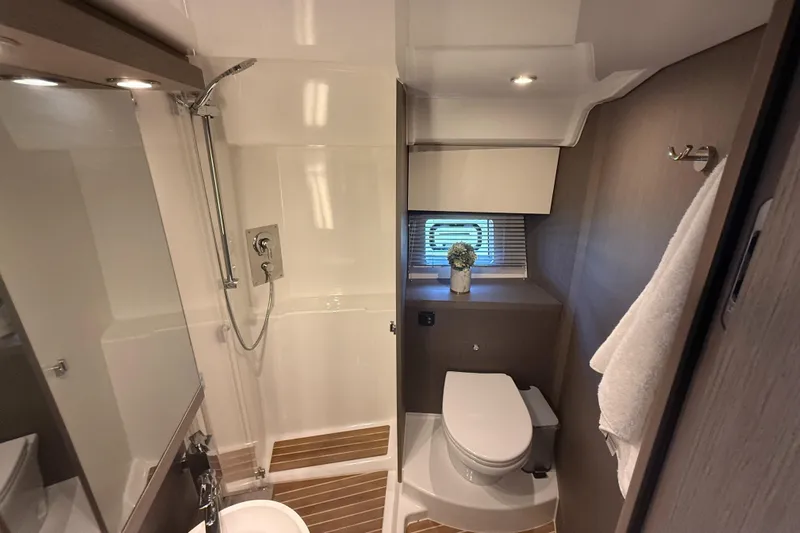  Yacht Photos Pics Modern bathroom in 2023 Beneteau Gran Turismo 45 yacht, featuring shower, toilet, and window.