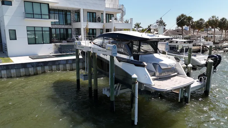  Yacht Photos Pics 2023 Beneteau Gran Turismo 45 yacht docked near modern waterfront home.