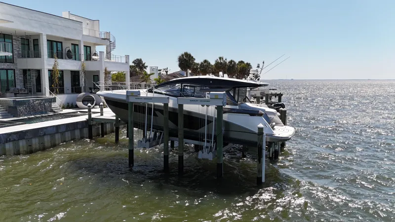  Yacht Photos Pics 2023 Beneteau Gran Turismo 45 yacht docked by a modern waterfront home.