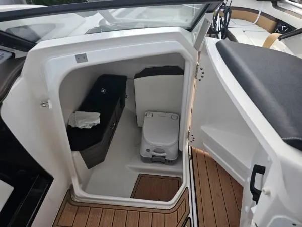  Yacht Photos Pics 2023 Yamaha Boats 275 SDX interior with compact marine toilet and wooden flooring.