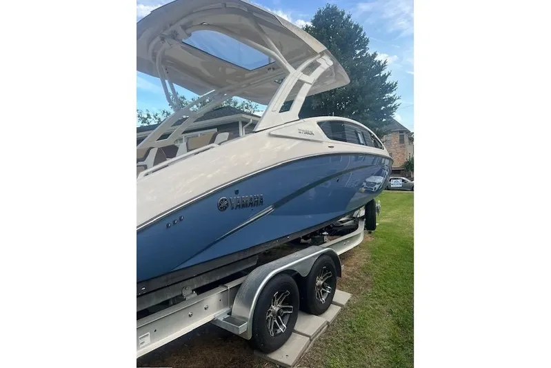  Yacht Photos Pics 2023 Yamaha Boats 275SDX on trailer, blue and white design, parked on grass.