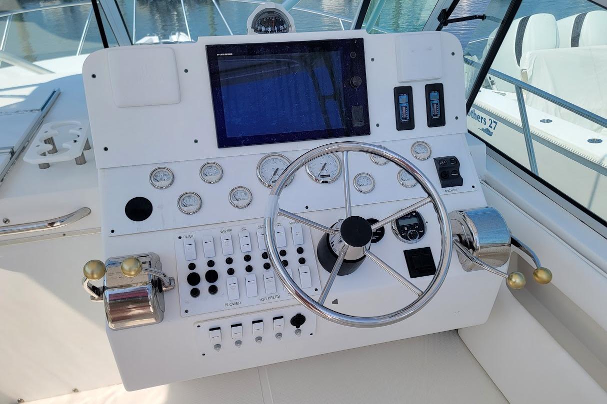 Control panel of a 2000 Stamas 310 Express boat with steering wheel and gauges.