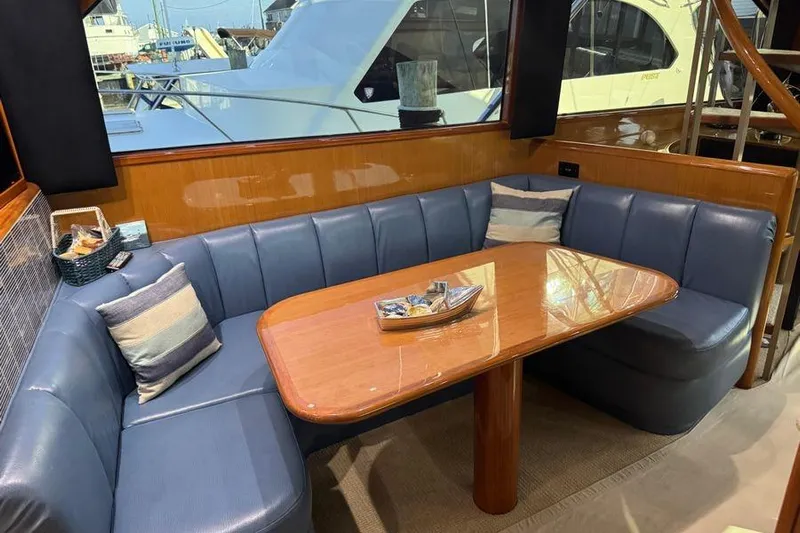 Miss Maggie Yacht Photos Pics Luxurious interior of 2002 Viking 61 Enclosed Bridge yacht with blue seating and wooden table.