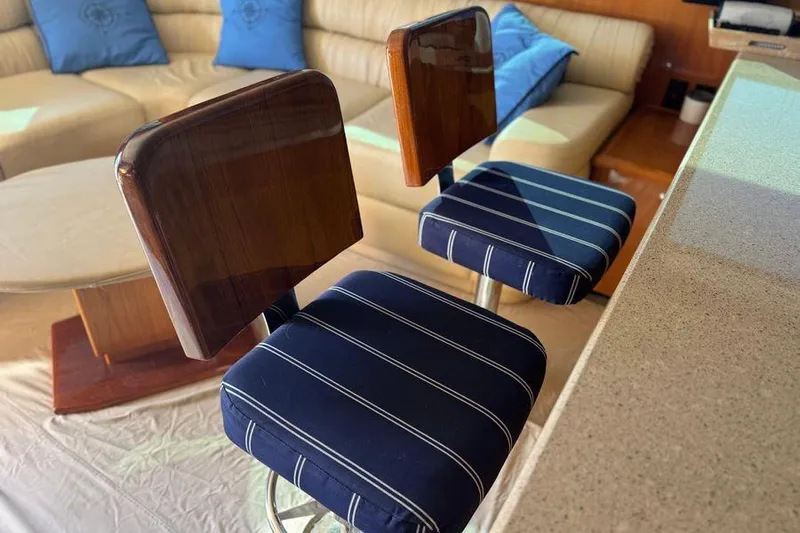 Miss Maggie Yacht Photos Pics Interior of 2002 Viking 61 Enclosed Bridge with striped bar stools and beige seating.