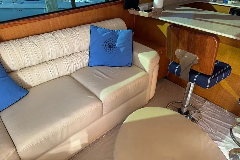 Miss Maggie Yacht Photos Pics Luxurious interior of 2002 Viking 61 Enclosed Bridge with cream sofa and blue cushions.