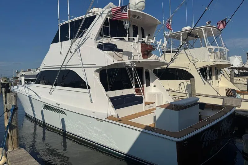 Miss Maggie Yacht Photos Pics 2002 Viking 61 Enclosed Bridge yacht docked at marina, featuring sleek design and American flags.