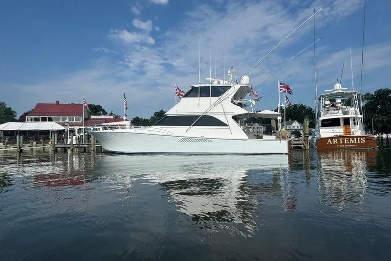 Miss Maggie Yacht Photos Pics 2002 Viking 61 Enclosed Bridge yacht docked at marina, flags displayed, clear sky.