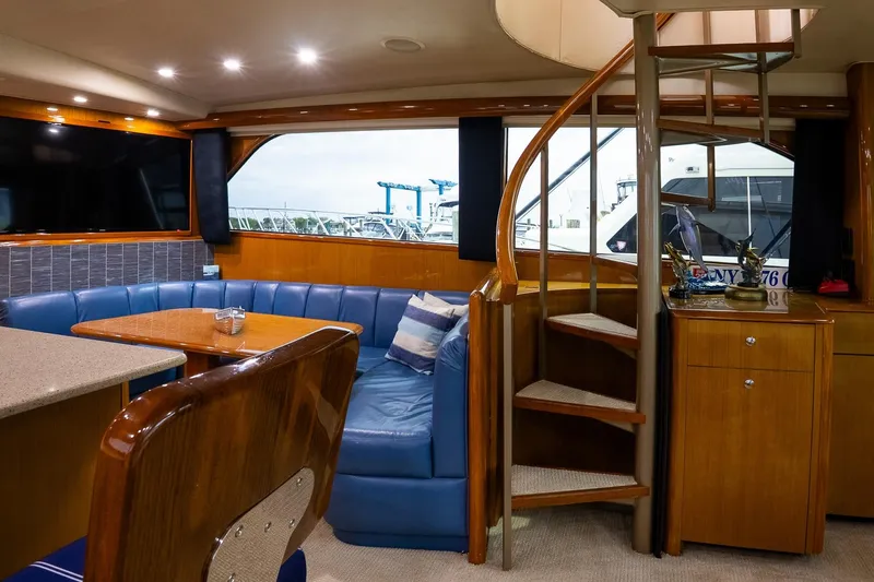 Miss Maggie Yacht Photos Pics Luxurious interior of 2002 Viking 61 Enclosed Bridge yacht with spiral staircase and seating area.