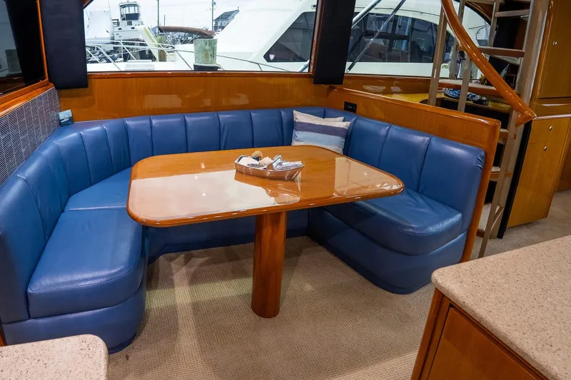 Miss Maggie Yacht Photos Pics Luxurious interior of 2002 Viking 61 Enclosed Bridge yacht with blue seating and wooden table.