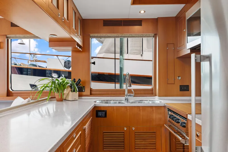 Tumbleweed Yacht Photos Pics Modern kitchen interior of 2016 North Pacific 49 Pilothouse yacht with wood cabinetry and stainless steel appliances.
