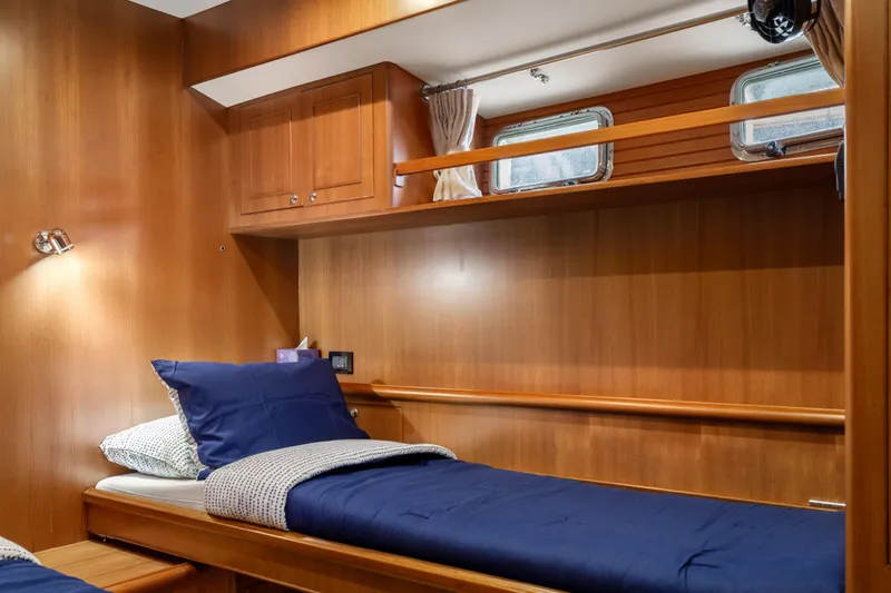 Tumbleweed Yacht Photos Pics Cozy cabin interior of 2016 North Pacific 49 Pilothouse with wooden finish and blue bedding.