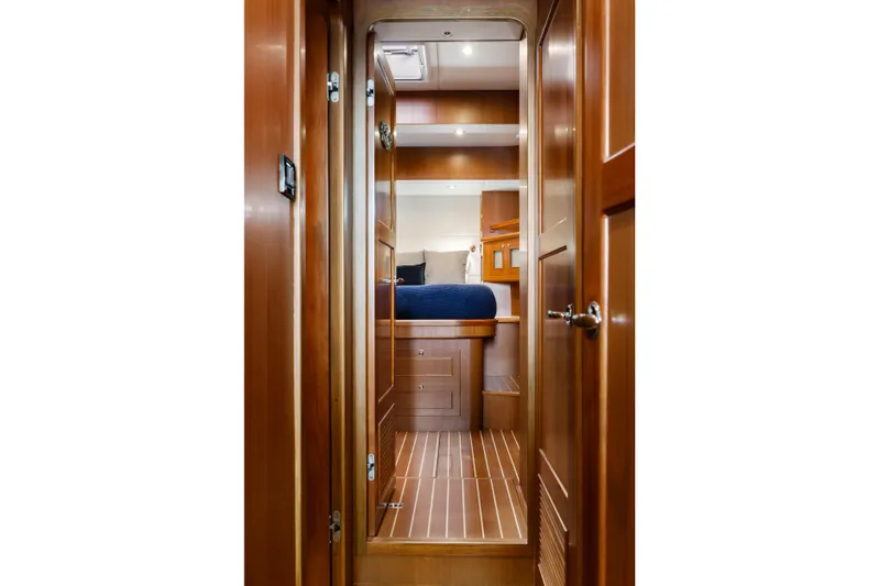 Tumbleweed Yacht Photos Pics Interior of 2016 North Pacific 49 Pilothouse, featuring wooden hallway and cozy bedroom.