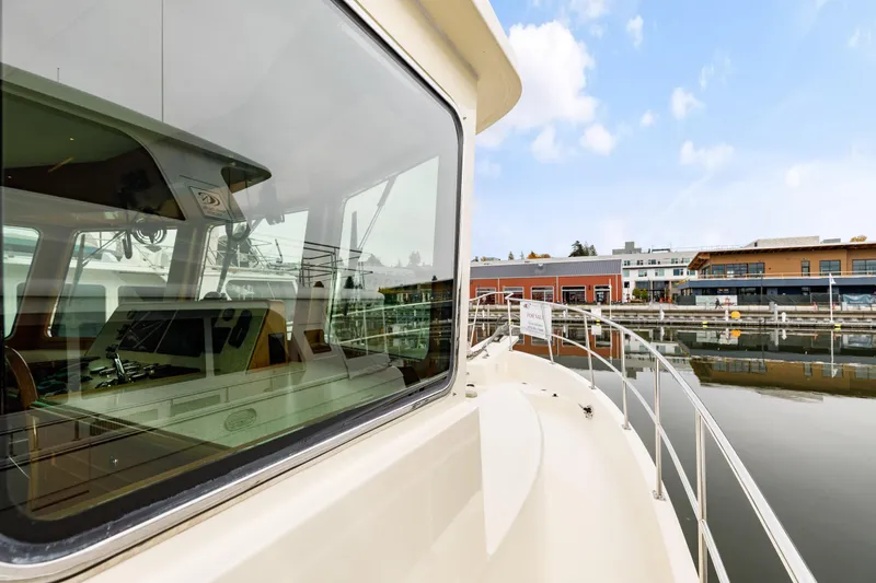 Tumbleweed Yacht Photos Pics 2016 North Pacific 49 Pilothouse yacht docked at marina, reflecting modern waterfront buildings.