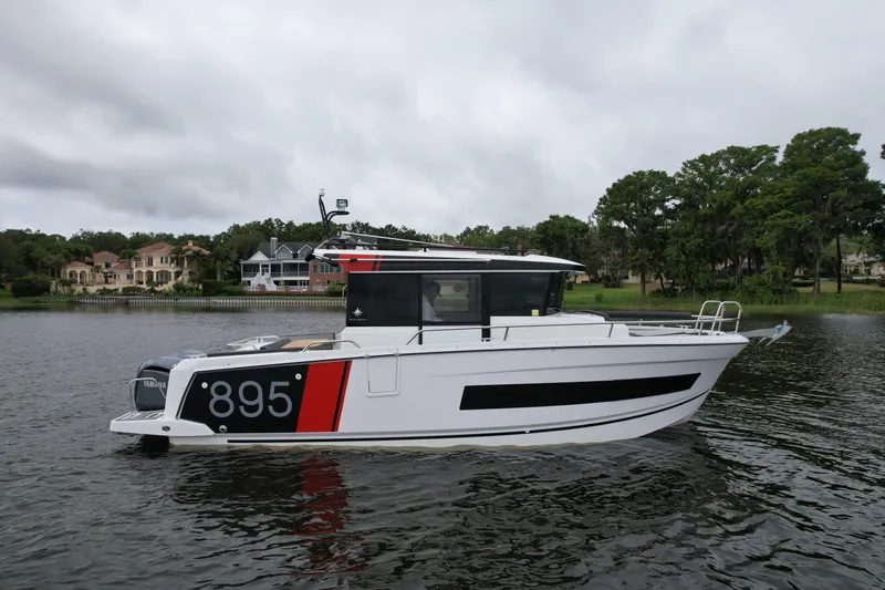  Yacht Photos Pics 2023 Jeanneau NC Sport 895 boat on a calm lake with trees in the background.