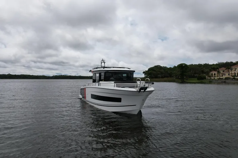  Yacht Photos Pics 2023 Jeanneau NC Sport 895 boat on a calm lake under cloudy skies.