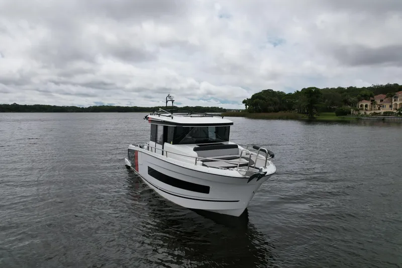  Yacht Photos Pics 2023 Jeanneau NC Sport 895 boat on a calm lake under cloudy skies.